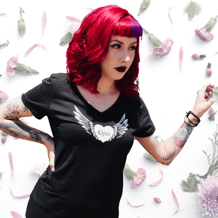 Rock your style with our hand-drawn Chica shirt, featuring a winged heart in classic chola print. Available in all sizes! Get yours today!