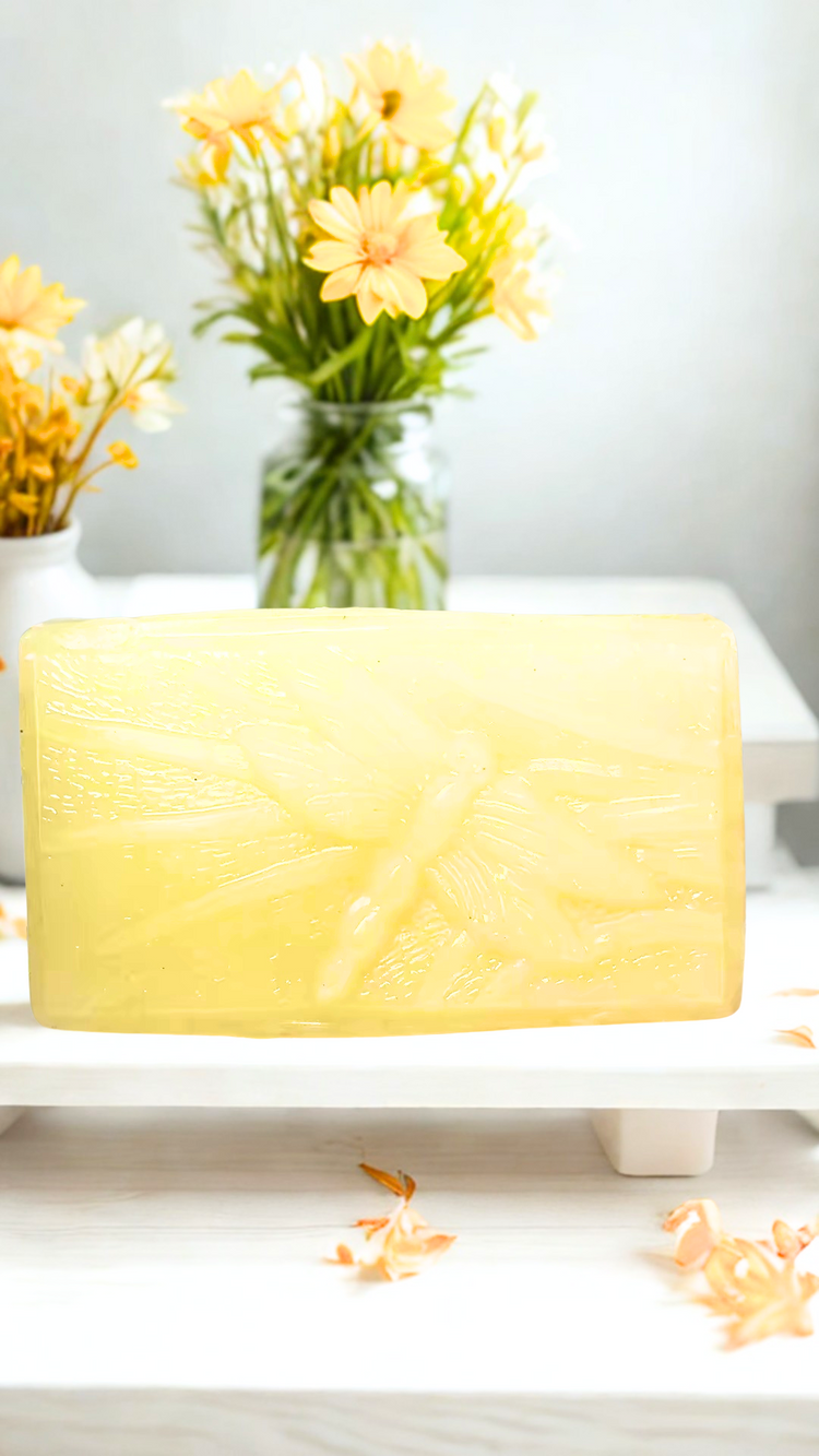 Dragonfly Fallen Leaves soap on a white surface with yellow flowers in the background