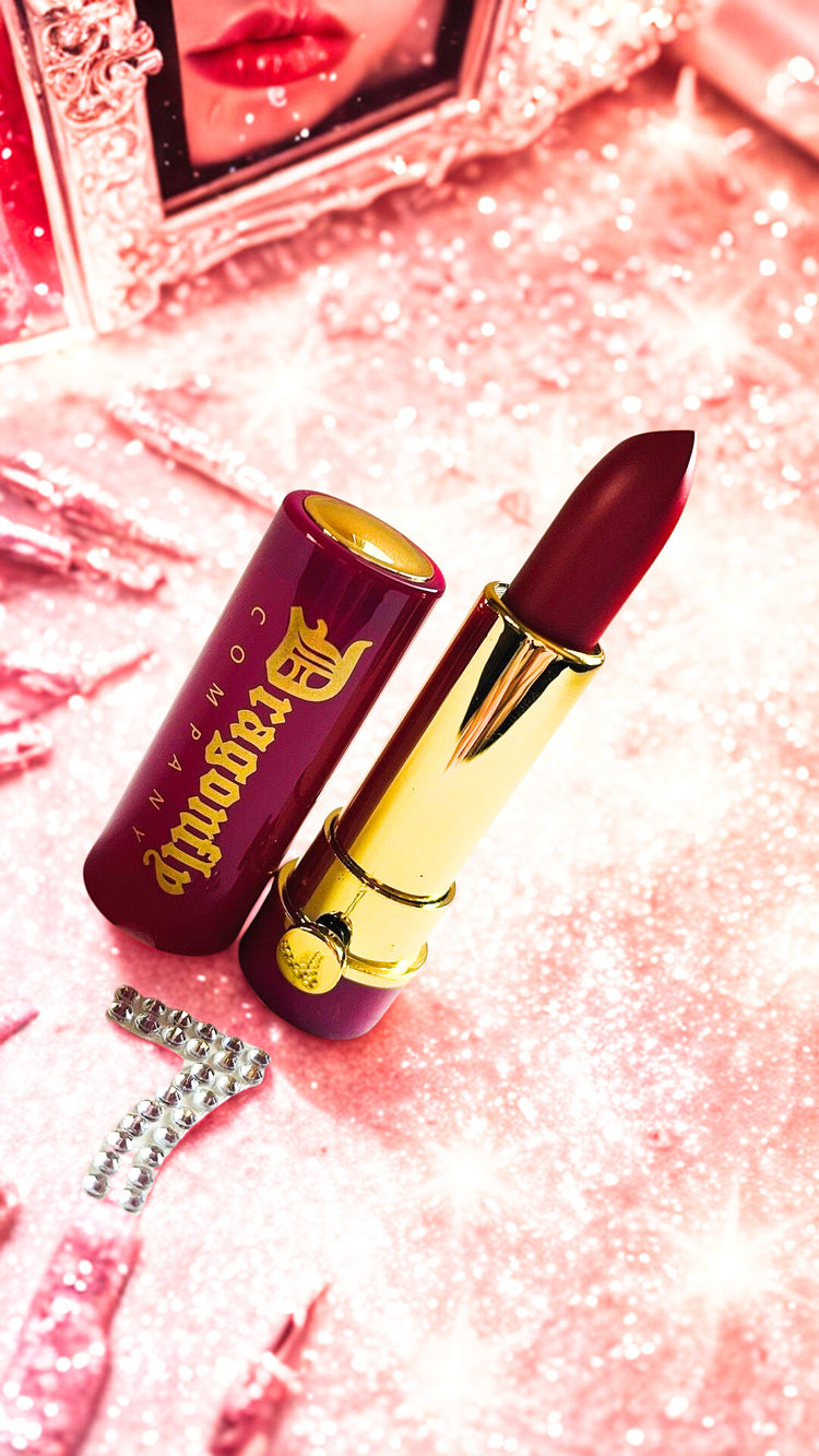 Lipstick with gold accents on a pink glittery background