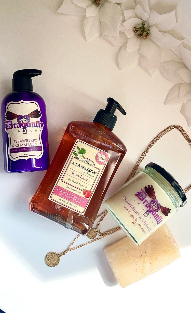 Strawberry and Champagne beauty products including a bottle, jar, and soap on a light background with flowers.