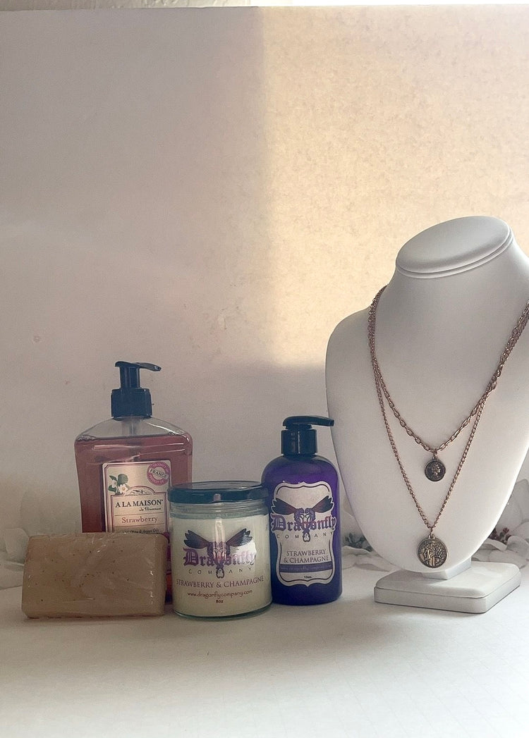 Strawberry and Champagne products including a necklace a white surface.