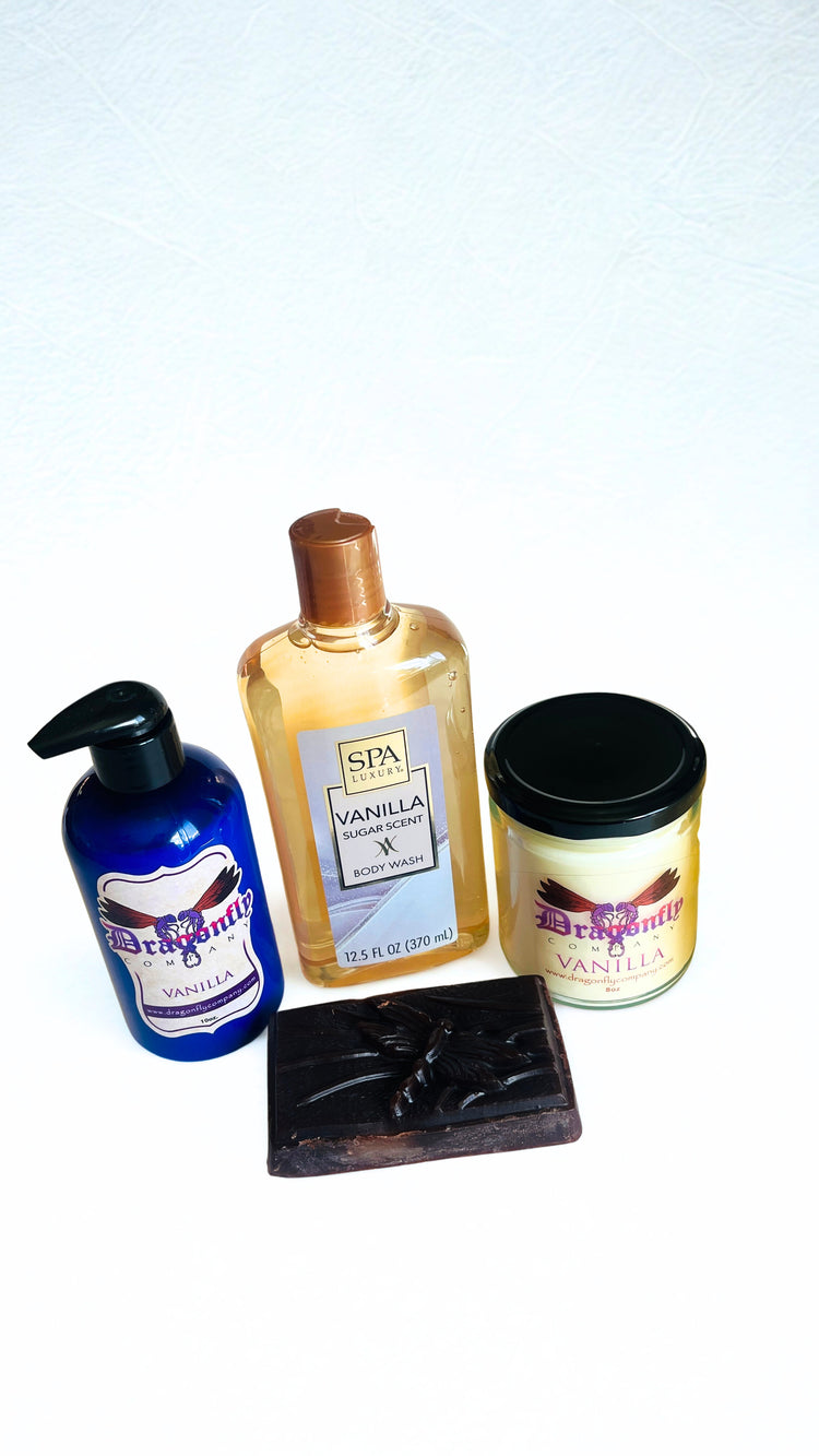 Set of spa products including a lotion, soap, candle body wash and shower puff on a white background