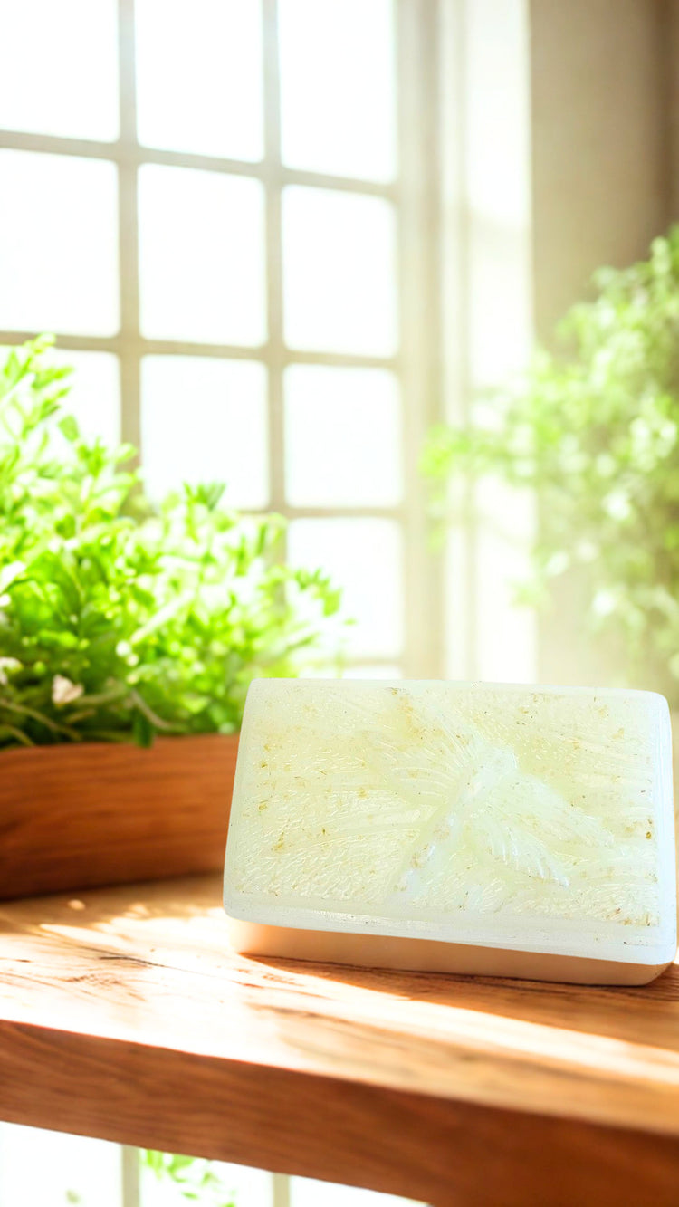 White bar of Clarity soap  on a wooden surface with plants in the background