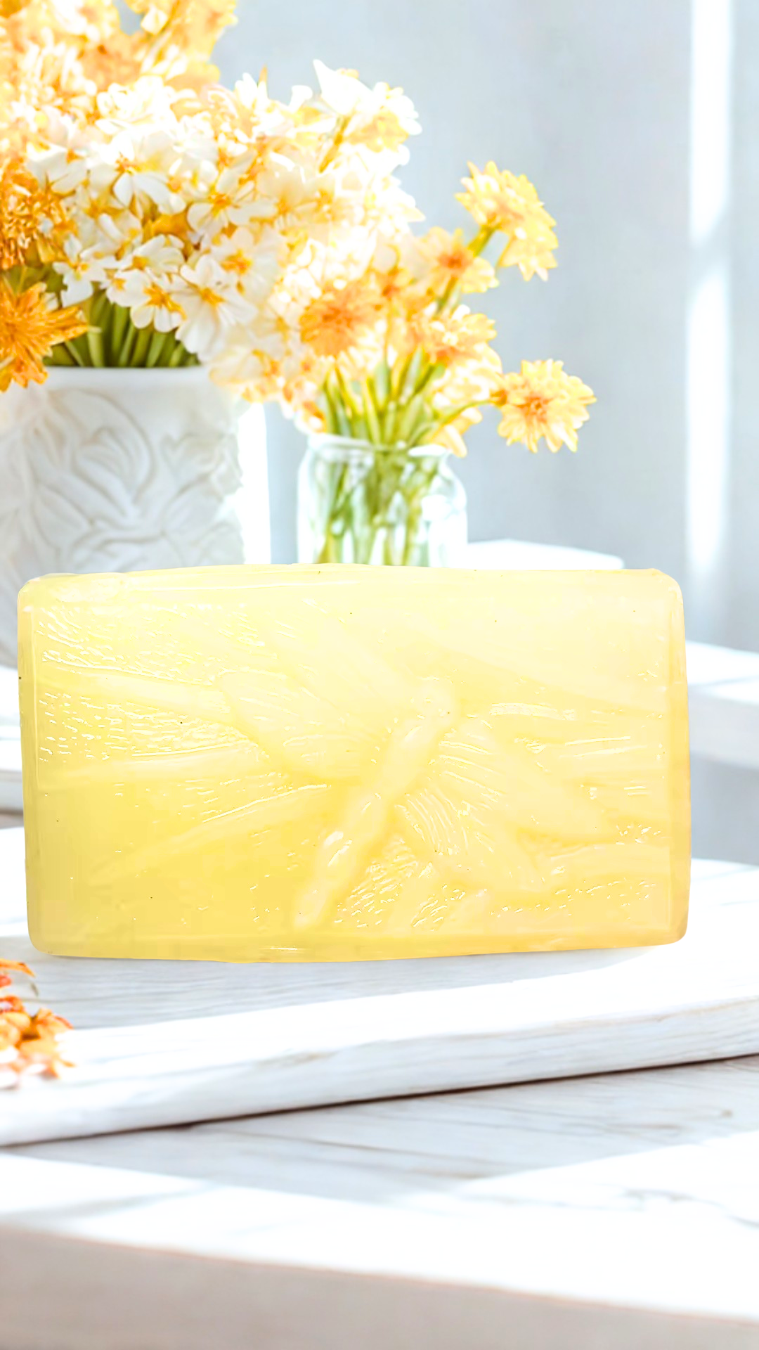 Fallen Leaves soap bar on a white surface with flowers in the background