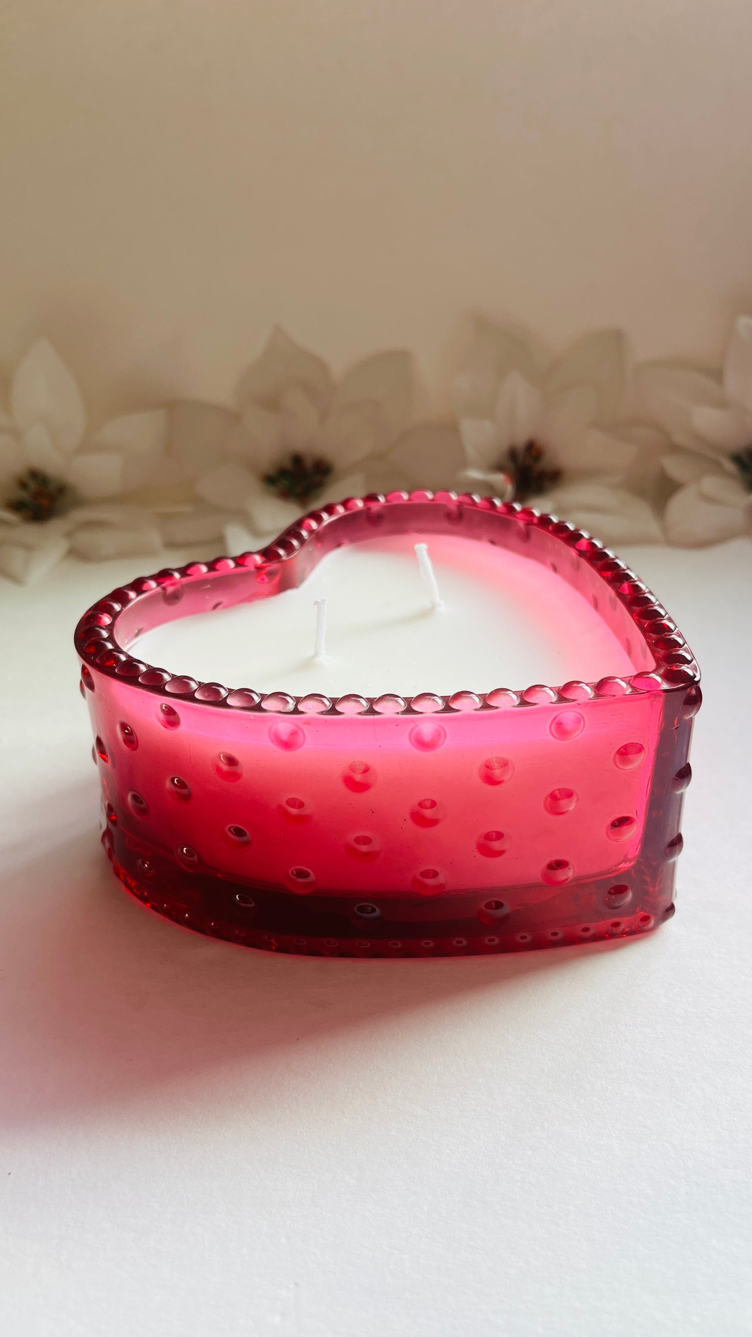 Heart-shaped pink candle on a light background