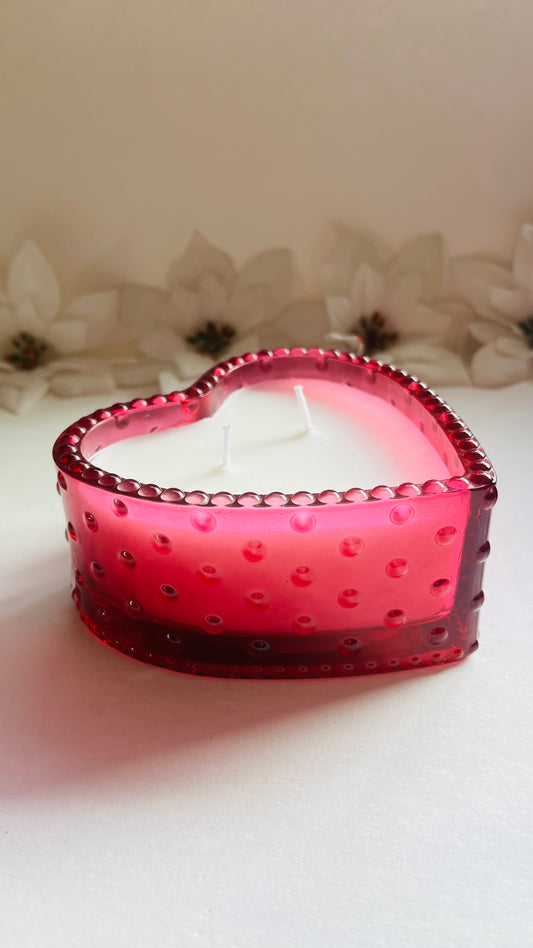Heart-shaped pink candle on a light background