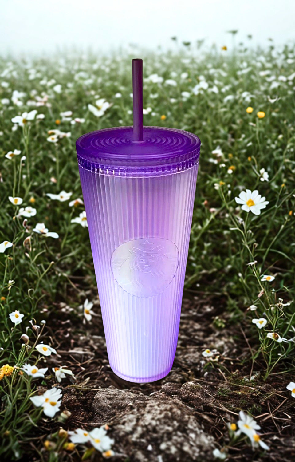 Lavender Starbucks tumbler with straw on a rock in a field of flowers