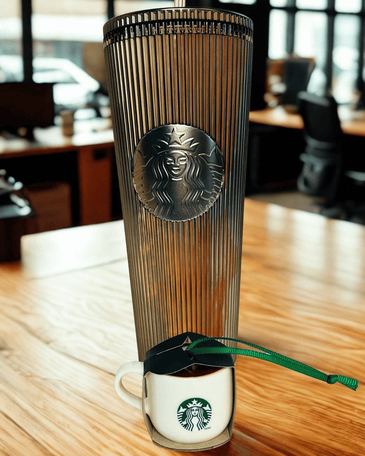 Starbucks tumbler  with lid on a wooden table in an office setting and ornament 
