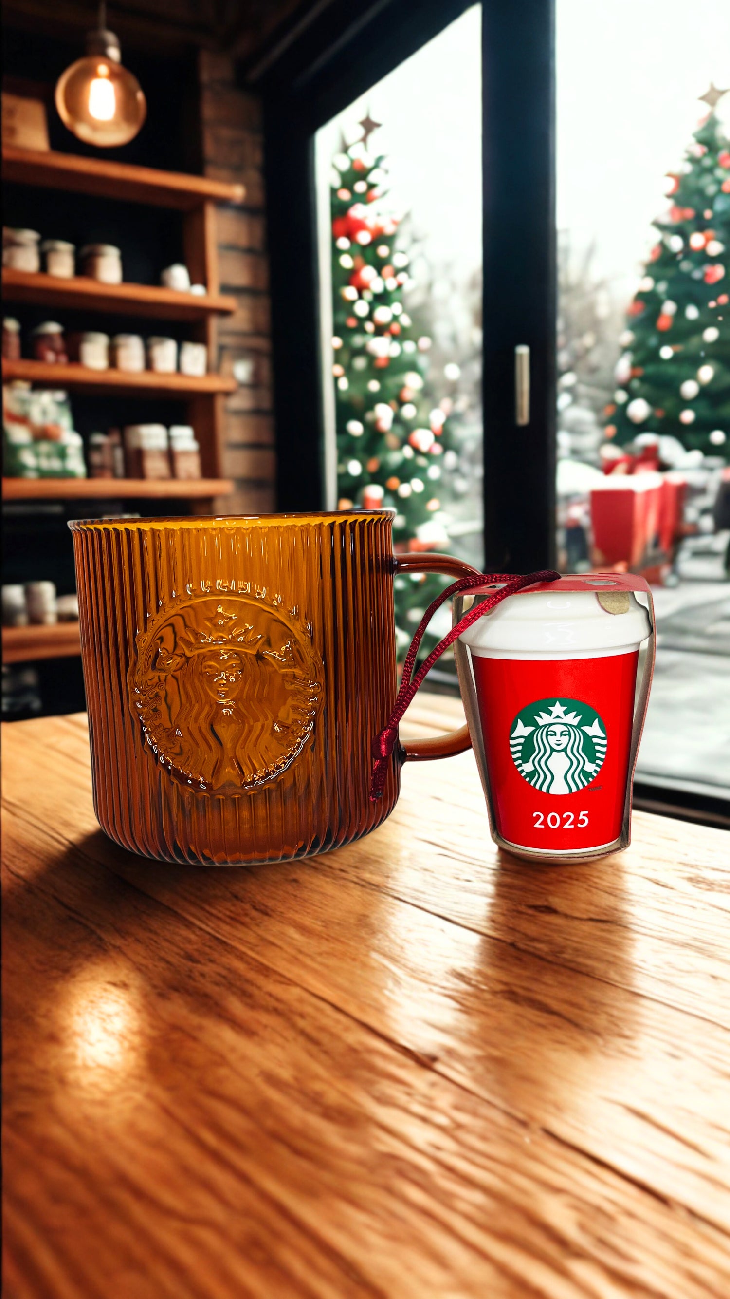 Starbucks mug and red ornament with 2025 design on a wooden table, Christmas trees visible through window.
