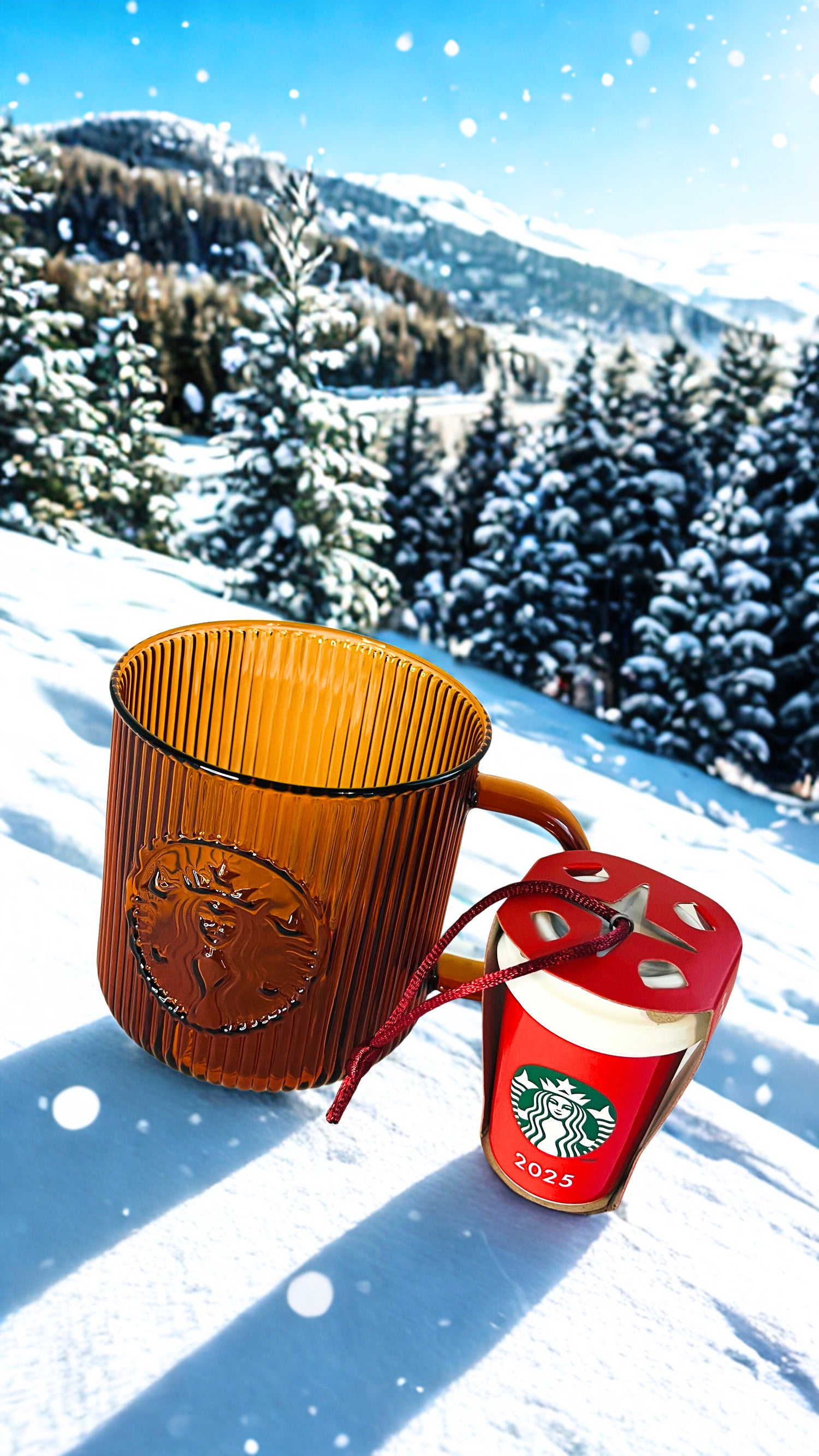 Amber Starbucks  mug and red Starbucks ornament in the snow with a mountainous background