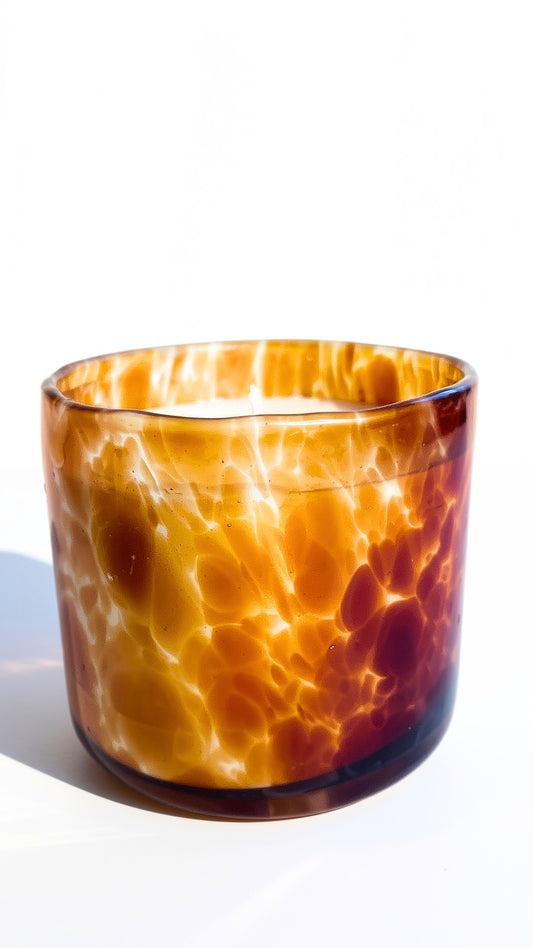 amber glass candle jar with a white wax surface, photographed on a clean white background with a soft shadow.